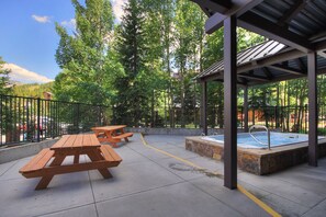 Een terras buiten met picknicktafels en een jacuzzi.