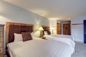 Een hotelkamer met twee bedden, houten hoofdeinden en bedlampjes.