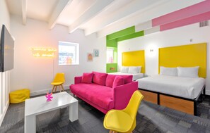 A modern hotel room with a pink sofa, yellow chairs, a white bed, and a neon sign. - The Gallatin(2 Queen Suite 115) Colorful Boutique Hotel! (Nashville)