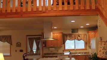 A spacious kitchen with wooden cabinets, a central island with stools, and a ceiling fan.