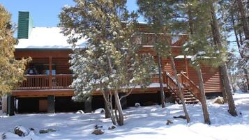 A cabin with a wooden deck and a staircase leading to a balcony.