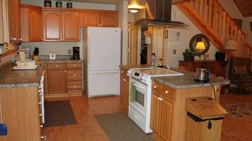 A kitchen with wooden cabinets, a refrigerator, an oven, and a sink.