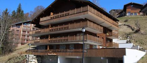 A multi-story hotel with wooden balconies and a stone facade.
