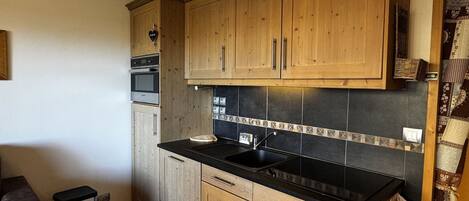 A kitchen with wooden cabinets, a black countertop, and a tiled backsplash.