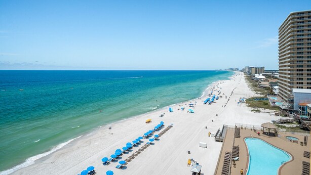 A beach resort with a pool, beach umbrellas, and a high-rise hotel. - Treasure Island 0903 (Panama City Beach)