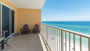 A balcony with two Adirondack chairs, a small table, and a view of the ocean. - Treasure Island 0903 (Panama City Beach)