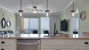 A modern kitchen with a large island, a ceiling fan, and a view to the outside. - Treasure Island 0903 (Panama City Beach)