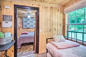 A wooden cabin room with two beds, a calendar, and a window with a view of greenery. - 'The Creek' Winfield Gem: 73 Acres of Privacy (Winfield)