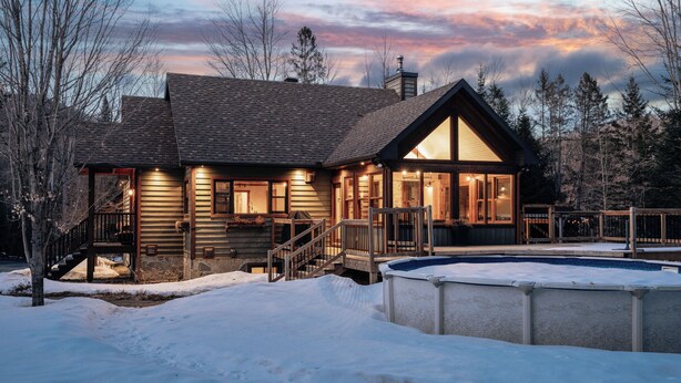 Una cabaña de troncos con piscina, rodeada de nieve.