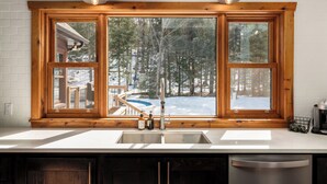 Una cocina con un amplio ventanal que da a un bosque nevado.