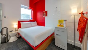 A hotel room with a bed, a small desk, a mirror, a window, a white cabinet, and a red chair. - The Gallatin (Cozy Full 113) 3 Miles to Downtown! (Nashville)