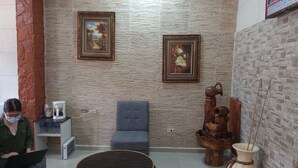 A room with a stone wall, a blue sofa, a round table, a coffee machine, and a decorative water feature. - Hotel Piedras Bonitas (Siguatepeque)