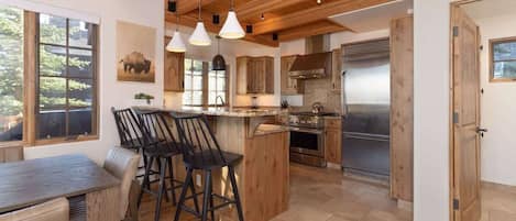 Una cocina amplia con vigas de madera, una isla central con taburetes de bar y un refrigerador grande.