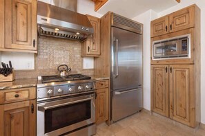 A kitchen with wooden cabinets, a stainless steel stove, and a built-in microwave. - Ski-In/Ski-Out Big Sky Home with Incredible Views (Big Sky)