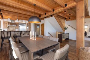 A spacious dining area with a large wooden table, leather chairs, and pendant lighting.