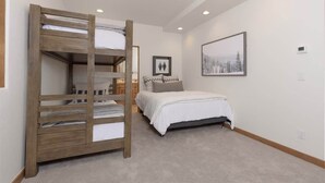 A bedroom with a bunk bed, a single bed, a framed picture on the wall, and a ceiling light. - Ski-In/Ski-Out Big Sky Home with Incredible Views (Big Sky)