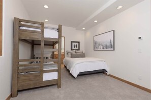 A bedroom with a bunk bed, a single bed, a framed picture on the wall, and a ceiling light. - Ski-In/Ski-Out Big Sky Home with Incredible Views (Big Sky)