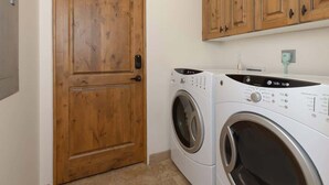 A laundry room with a wooden door and two washing machines. - Ski-In/Ski-Out Big Sky Home with Incredible Views (Big Sky)