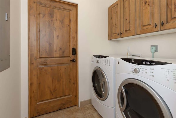 A laundry room with a wooden door and two washing machines.
