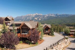 A lodge with a wooden exterior, a covered porch, and a view of mountains in the background.
