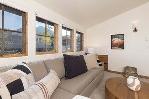 Un salon avec un canapé, une table basse ronde en bois et une lampe.