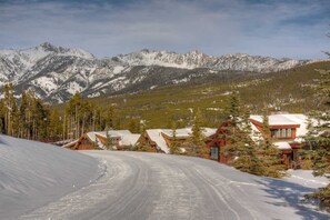 A snow-covered mountain landscape with wooden cabins and a clear sky.