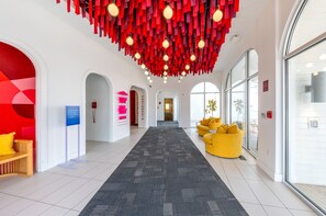 A hotel lobby with a central carpeted walkway, red hanging decor, and a yellow sofa. - The Gallatin (114) Only 3 miles to Downtown! (Nashville)