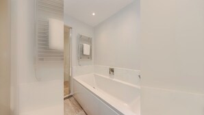 Une salle de bain moderne avec une douche à l’italienne, une baignoire et un porte-serviettes.