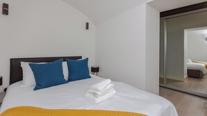 A hotel room with a bed, pillows, a lamp, and a mirror. - Spacious and Modern 2BD Flat in Pimlico (London)