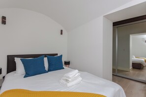 A hotel room with a bed, pillows, a lamp, and a mirror. - Spacious and Modern 2BD Flat in Pimlico (London)