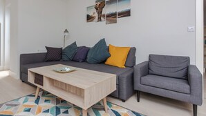 A modern living room with a grey sofa, a wooden coffee table, and a patterned rug.