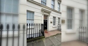 A white building with a black metal fence, a door, and windows.