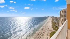 A beach view with a clear sky, a sandy beach, and a building with balconies. - Treasure Island 1806 (Panama City Beach)