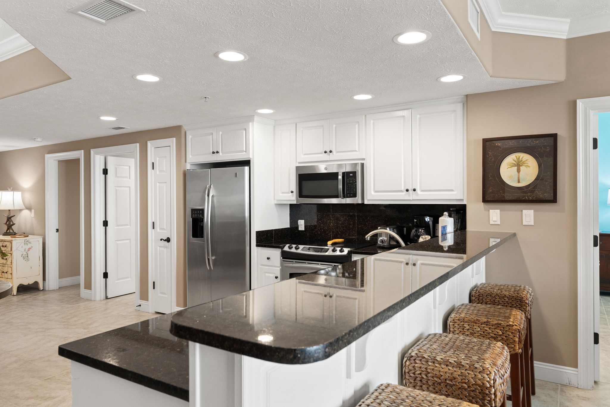 A modern kitchen with white cabinets, stainless steel appliances, and a black granite countertop.