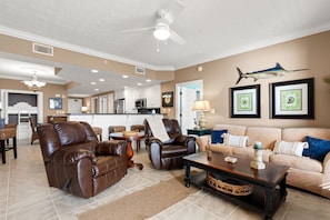 A spacious living area with leather sofas, a coffee table, and a ceiling fan.