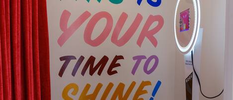 Une pièce avec un message motivant écrit sur le mur, un miroir de coiffeuse et un rideau rouge.