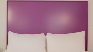 Ein Bett mit einem violetten Kopfteil und weißen Kissen.