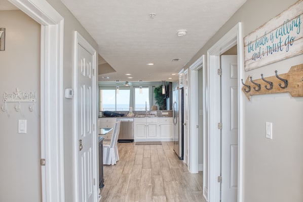 A kitchen with white cabinets, a large window, and a view of the ocean. - Treasure Island 1811 (Panama City Beach)