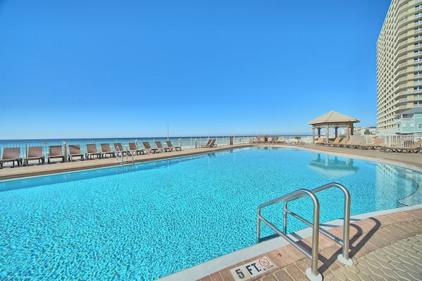 Relax by the expansive pool surrounded by lounge chairs and a gazebo.