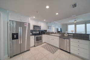 Enjoy cooking in this well-equipped kitchen with stainless steel appliances, white cabinetry, and a granite countertop.
