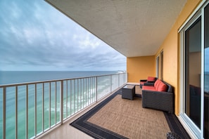 Enjoy the ocean view from this balcony with a comfortable sofa, table, and rug.