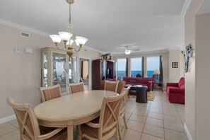 Ein großzügiger Wohnbereich mit Esstisch und Stühlen, einem roten Sofa und Blick auf den Ozean.