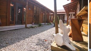 Um edifício de madeira com galeria coberta e uma grande escultura branca ao primeiro plano.