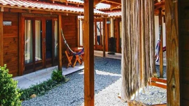 Uma cabana de madeira com varanda coberta, rede e um adorno pendurado.