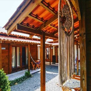 A wooden cabin with a covered patio, a hammock, and a hanging decoration.