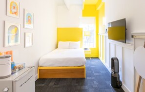 A hotel room with a bed, a television, a desk with a computer, and framed artwork on the wall. - The Gallatin(214) Colorful Boutique Hotel (Nashville)