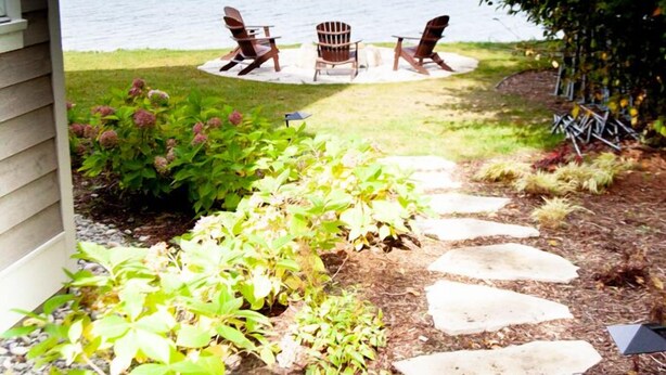 A pathway leading to a deck with Adirondack chairs overlooking a body of water. - 4678 on Glen Lake - Beautiful Luxury Cottage (Maple City)