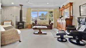 A cozy living room with a fireplace, leather furniture, and a view of the outdoors. - Pukeko Lodge - Tūrangi Holiday Home (Turangi)