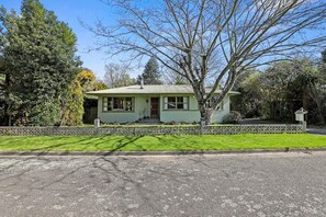 A single-story house with a front porch, surrounded by a decorative fence and lush greenery. - Pukeko Lodge - Tūrangi Holiday Home (Turangi)