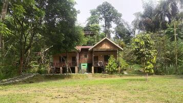 Une maison de campagne à l’aspect rustique, avec une façade en briques, un porche en bois et une porte verte.